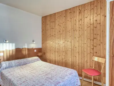 a bedroom with a bed and a wooden wall at Appartement 2 pièces avec balcon et parking à Megève - FR-1-453-120 in Megève