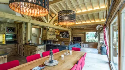 a dining room with a wooden table and red chairs at Chalet Chal'heureux in Chamonix-Mont-Blanc