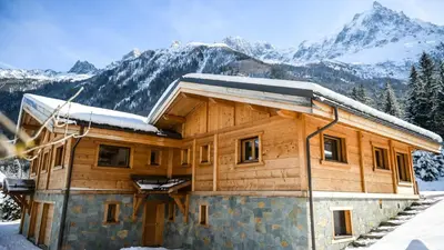 a wooden house with mountains in the background at Chalet Chal'heureux + Annexe in Chamonix-Mont-Blanc