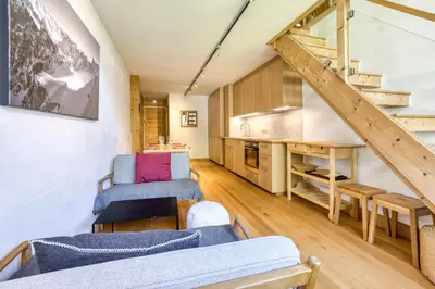 a living room with blue chairs and a staircase at Brévent Loft Cozy 3-bedroom duplex 250m to Planpraz cable car in Chamonix-Mont-Blanc