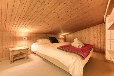 a bedroom with a bed in a room with wooden walls at Brévent Loft Cozy 3-bedroom duplex 250m to Planpraz cable car in Chamonix-Mont-Blanc