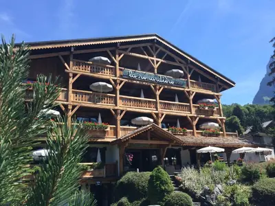 a large wooden building with a balcony with umbrellas at Residence Hôtelière La Renardiere in Samoëns