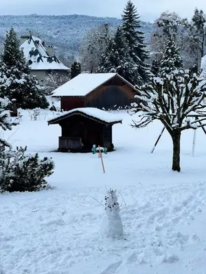 a snowman in the snow in front of a barn at Residence Hôtelière La Renardiere in Samoëns