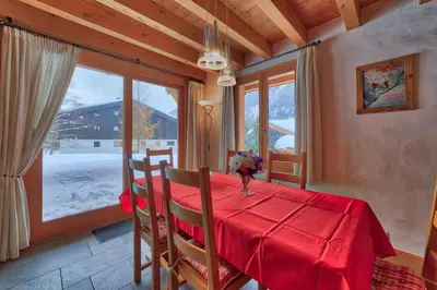 a dining room with a red table and a window at Chalet Coralie in Chamonix-Mont-Blanc