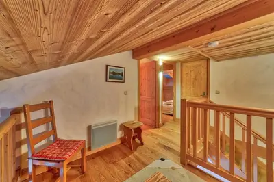 a room with a wooden staircase with a chair at Chalet Coralie in Chamonix-Mont-Blanc