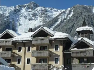 a building with snow on the roof with a mountain at La Ginabelle Chamonix in Chamonix-Mont-Blanc