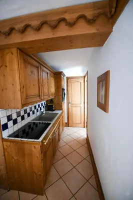 a kitchen with wooden cabinets and a tile floor at La Ginabelle Chamonix in Chamonix-Mont-Blanc