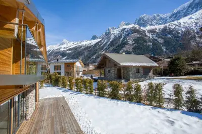 a house in the snow with mountains in the background at Chalet Montana- Chamonix All Year in Chamonix-Mont-Blanc