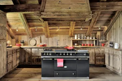 a black stove in a kitchen with wooden walls at Chalet Javen - 520m2 avec piscine chauffée et home cinéma in Megève