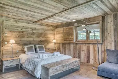 a bedroom with a bed in a wooden wall at Chalet Javen - 520m2 avec piscine chauffée et home cinéma in Megève
