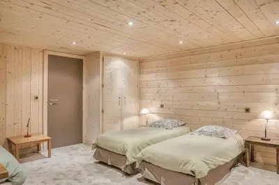 two beds in a room with wooden walls at Chalet Javen - 520m2 avec piscine chauffée et home cinéma in Megève