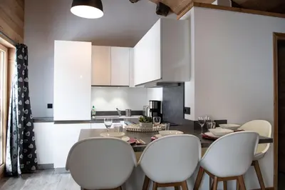 a kitchen with a dining table and white chairs at Chalet Victoire in Chamonix-Mont-Blanc