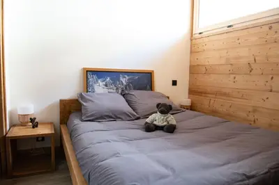 a teddy bear sitting on a bed in a bedroom at Chalet Victoire in Chamonix-Mont-Blanc
