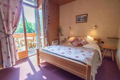 a bedroom with a bed and a large window at Résidence La Cour in Samoëns