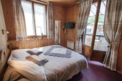a bedroom with a bed in a room with windows at Résidence La Cour in Samoëns