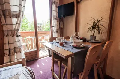 a dining room table and chairs with a table and a window at Résidence La Cour in Samoëns