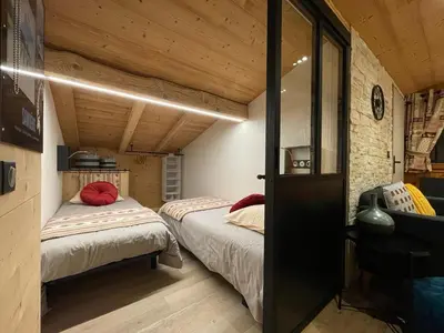 two beds in a small room with wooden ceilings at Résidence La Cour in Samoëns