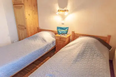 two twin beds in a room with a night stand at Appartements Giffre et Clesson - DAHU COMPAGNIE in Samoëns