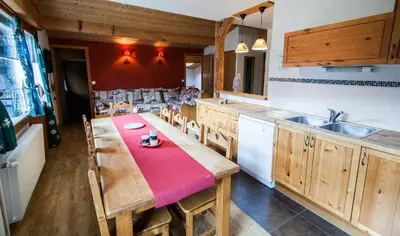 a kitchen with a wooden table with a red table cloth at Appartements Giffre et Clesson - DAHU COMPAGNIE in Samoëns