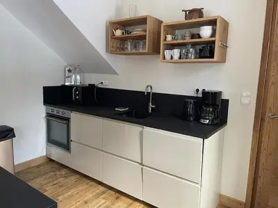 a kitchen with white cabinets and a black counter top at Chalet des glaciers in Chamonix-Mont-Blanc