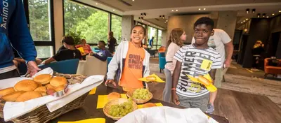 two children standing in front of a table of food at Hôtel Club MMV Le Flaine in Flaine