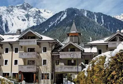 a large building with snowy mountains in the background at La Ginabelle Gala in Chamonix-Mont-Blanc