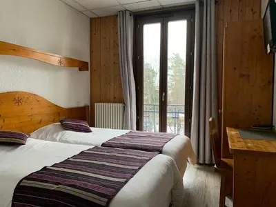 a bedroom with two beds and a large window at Hotel des Lacs in Chamonix-Mont-Blanc