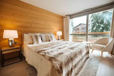 a bedroom with a bed and a chair and a window at Megève Great apartment Lesporting Ski - AE 303 in Megève