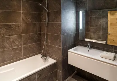 a bathroom with a tub and a sink and a mirror at Megève Great apartment Lesporting Ski - AE 303 in Megève