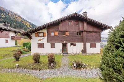 a large wooden house in the middle of a field at Alpage: Residence Brevent in Les Houches