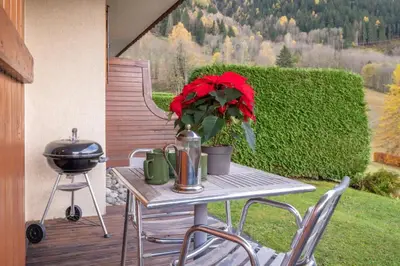 a table with a flower on a patio with a grill at Alpage: Residence Brevent in Les Houches