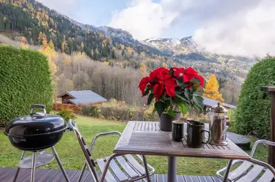 a table with a grill and flowers on a patio at Alpage: Residence Brevent in Les Houches