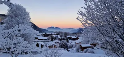 a village covered in snow with mountains in the background at Demi-Chalet Le Bief --Prox pistes in Les Carroz d'Araches