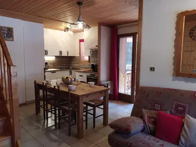 a kitchen with a wooden table with chairs and a dining room at Appartement L'Ecureuil 8 pers -Prox pistes et centre village- in Les Carroz d'Araches