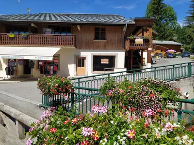 a house with flowers in front of a fence at Appartement L'Ecureuil 8 pers -Prox pistes et centre village- in Les Carroz d'Araches