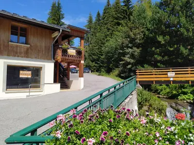 a building with a green fence next to flowers at Appartement L'Ecureuil 8 pers -Prox pistes et centre village- in Les Carroz d'Araches