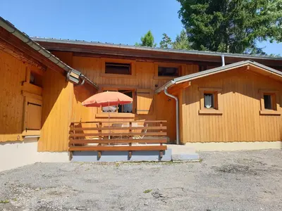 a bench with an umbrella in front of a building at Demi-Chalet l'Ancolie -- Prox pistes in Les Carroz d'Araches
