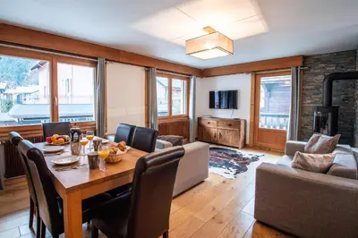 a dining room with a table and a living room with a fireplace at Mintaka Apartment - Chamonix in Chamonix-Mont-Blanc