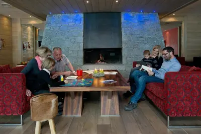 a family sitting in a living room with a fireplace at CGH Résidence Boutique Le Centaure in Flaine