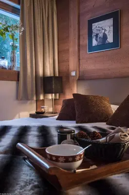 a table with a bowl of food on top of a bed at CGH Résidence Boutique Le Centaure in Flaine