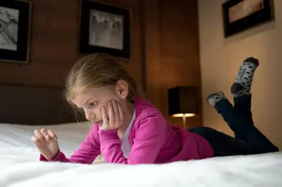 a little girl laying on a bed at CGH Résidence Boutique Le Centaure in Flaine
