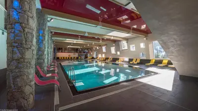 a large swimming pool in a building with chairs around it at CGH Résidence Boutique Le Centaure in Flaine