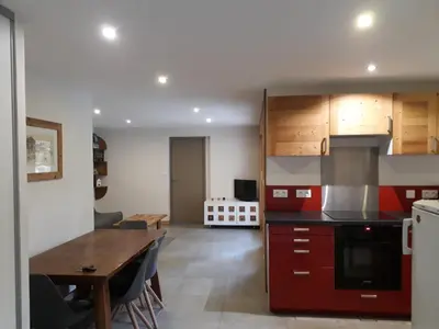 a kitchen with red cabinets and a wooden table at Appartement rez de jardin in Saint-Gervais-les-Bains