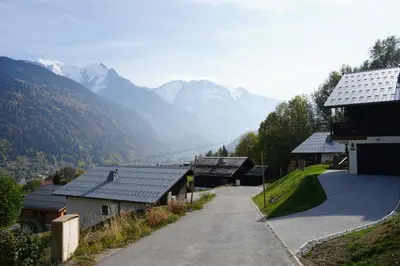 a road in a village with mountains in the background at Chalet Kizuna in Saint-Gervais-les-Bains