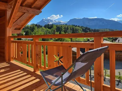 a rocking chair on a deck with mountains in the background at Chalet Arpitan - les Carroz - Grand Massif in Les Carroz d'Araches