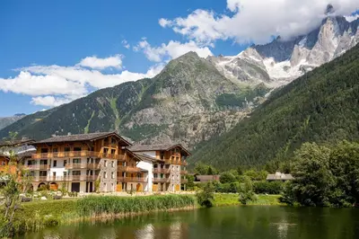 a building next to a river with mountains in the background at La Cordee 412 Apartment - Chamonix All Year in Chamonix-Mont-Blanc