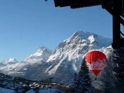 a red balloon flying over a snow covered mountain at Grangettes in Les Carroz d'Araches