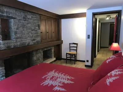 a bedroom with a red bed and a fireplace at Grangettes in Les Carroz d'Araches