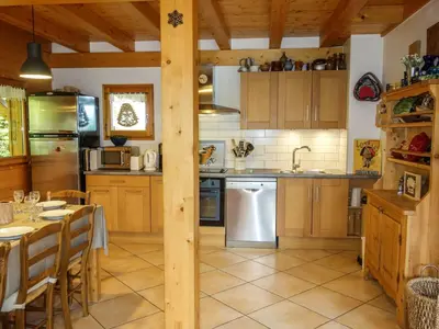 a kitchen with wooden cabinets and a table and a kitchen with a table and chairs at Chalet du Bulle by Interhome in Saint-Gervais-les-Bains