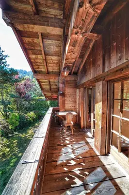 a porch of a wooden house with a table and chairs at Thendia Montblanc in Les Houches